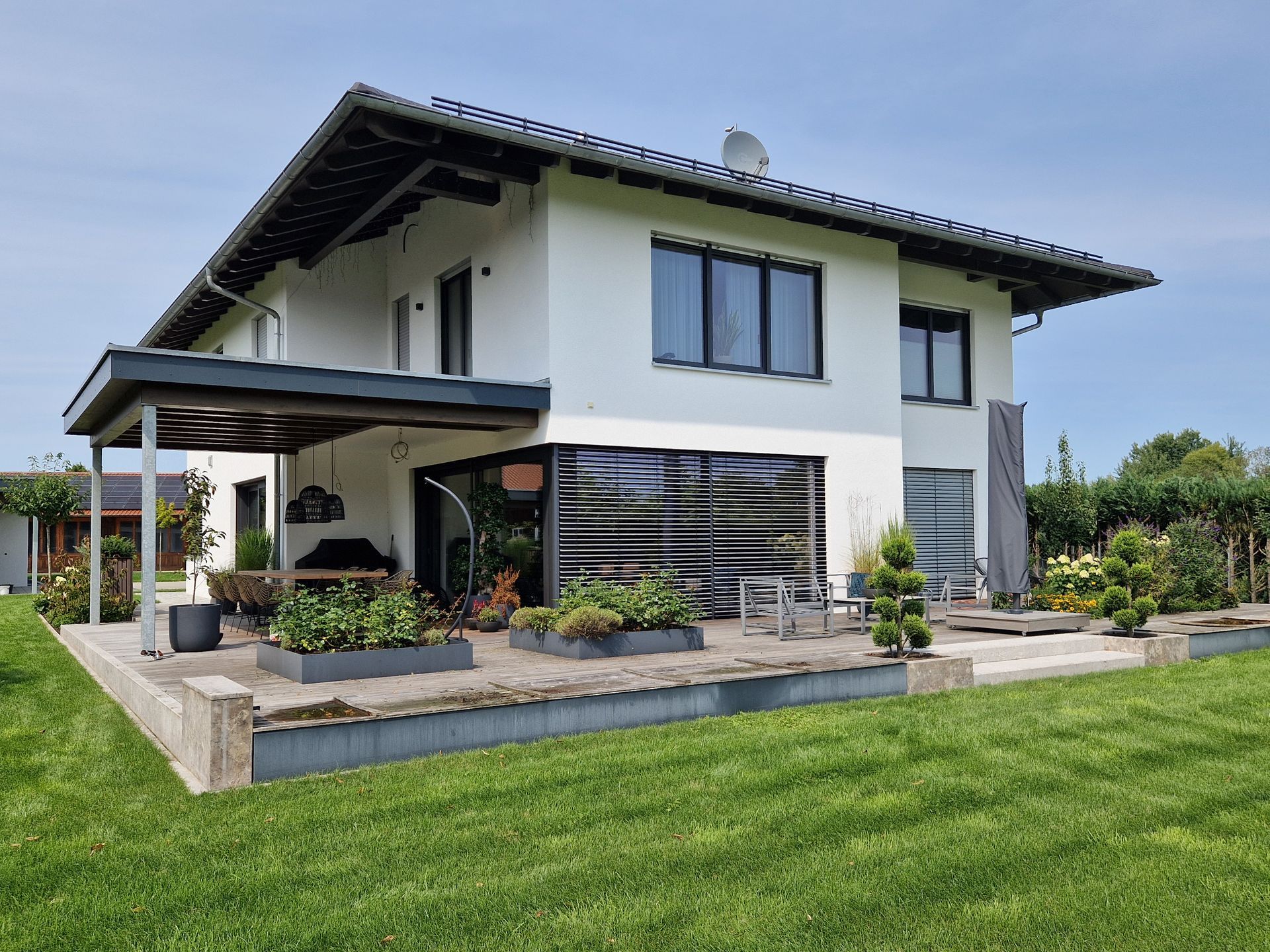 Modernes Haus mit weißer Fassade, Garten und einer Pegola