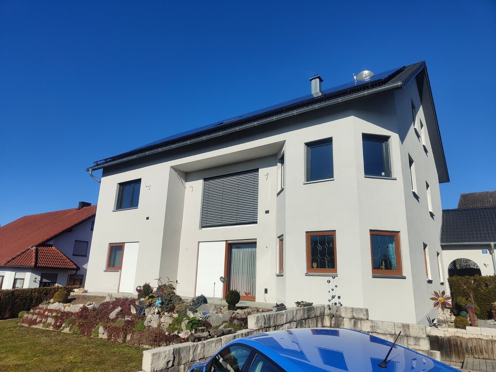 Großes Haus mit weißer Fassade und dunklem Dach