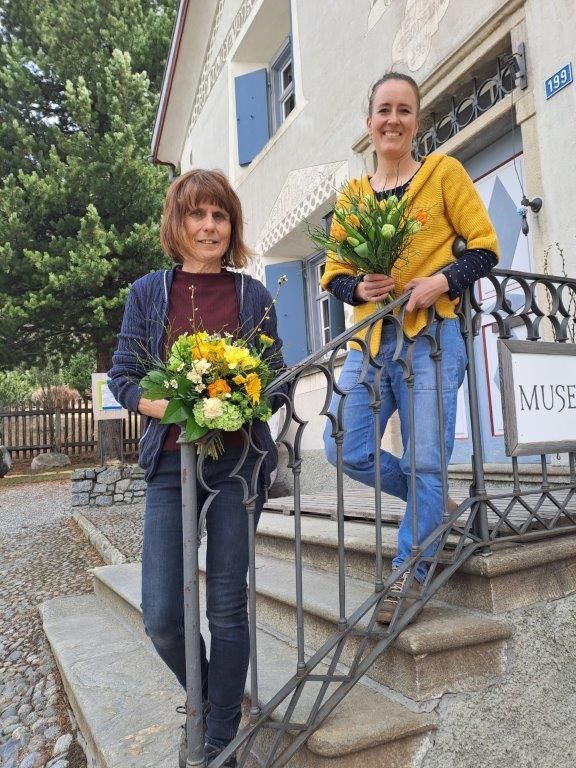 Susanne Kündig (Inhaberin) und Rosalia Furger (langjährige Mitarbeiterin) miit buntem Blumenstrauss auf einer Aussentreppe