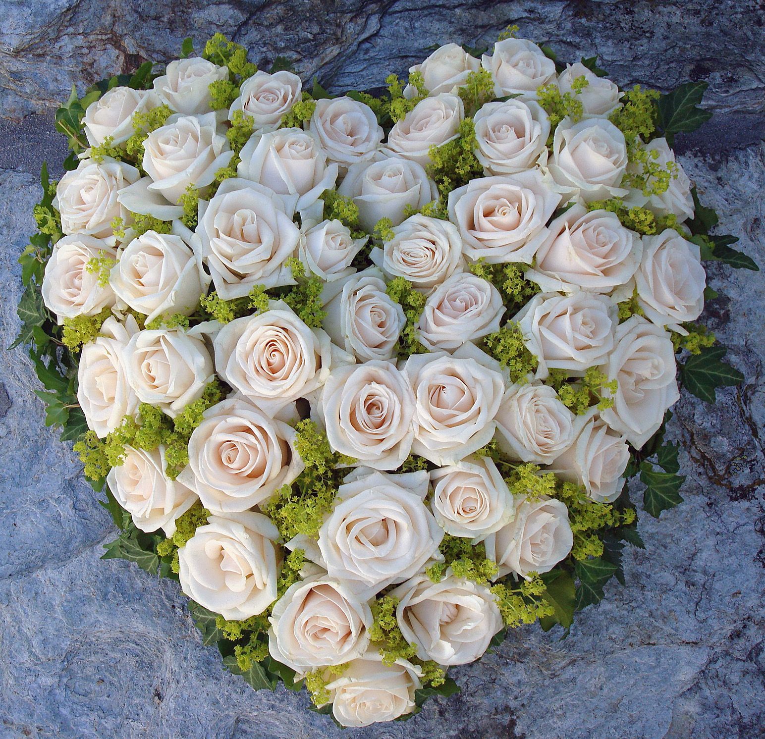 Auf einem Stein liegt ein Strauss weisser Blumen. Foto vom Blumen-Atelier BACCARA