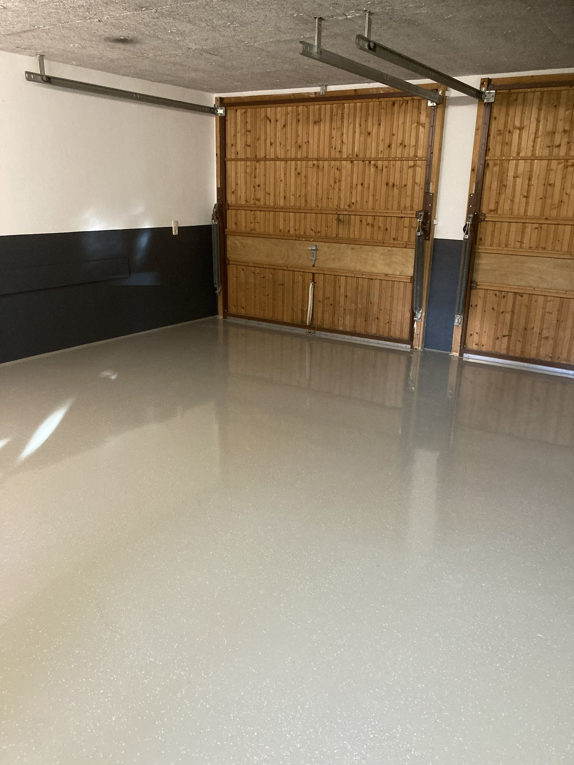 Auftragen einer glänzenden Versiegelung auf einen Holzboden mit einer Farbrolle.