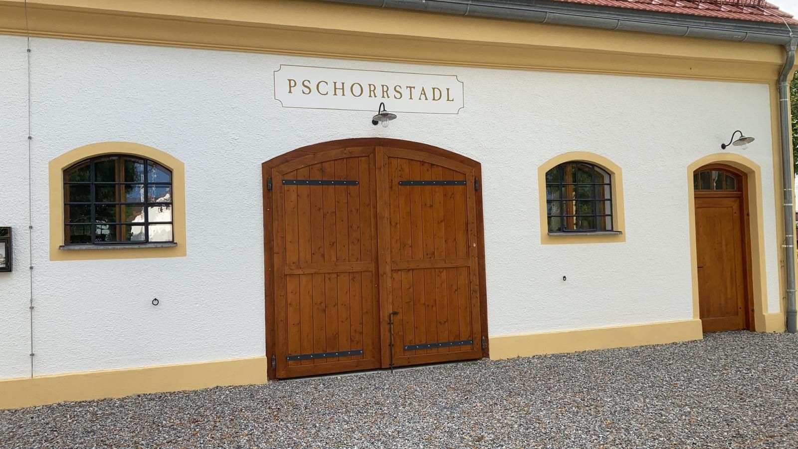 Graue Schindelverkleidung an einem Haus mit einem weiß getönten Fenster und einem Blumenbeet entlang eines Kieswegs.