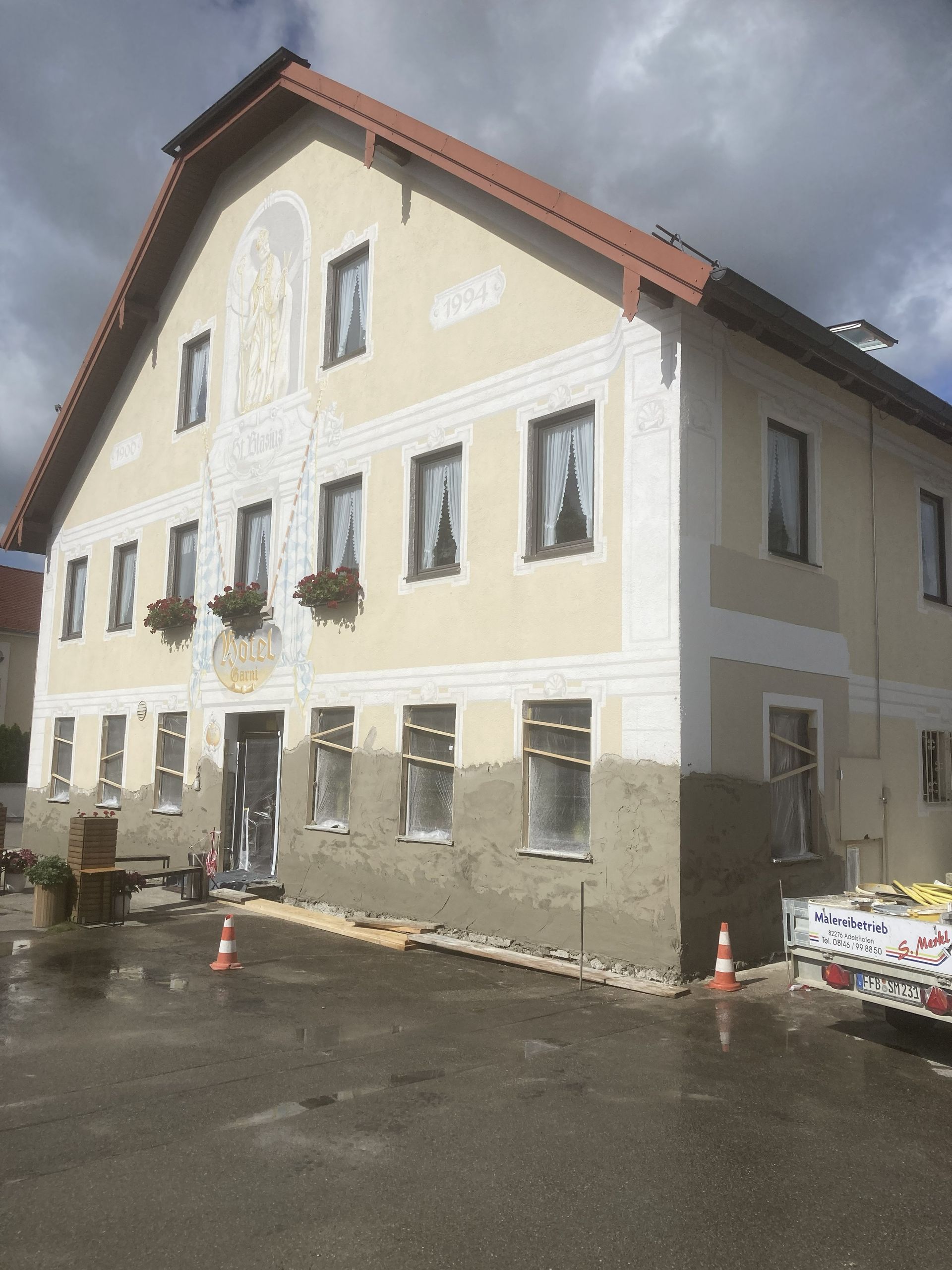 Ein Arbeiter streicht die Außenfassade eines Hochhauses, während er an Seilen hängt.