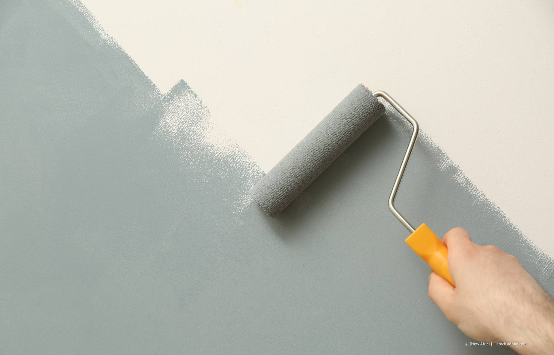 Graue Farbe mit einer Rolle auf eine weiße Wand auftragen.