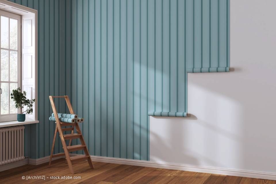 Zimmer mit Holzboden, Fenster und blau tapezierter Wand, mit einer Leiter.