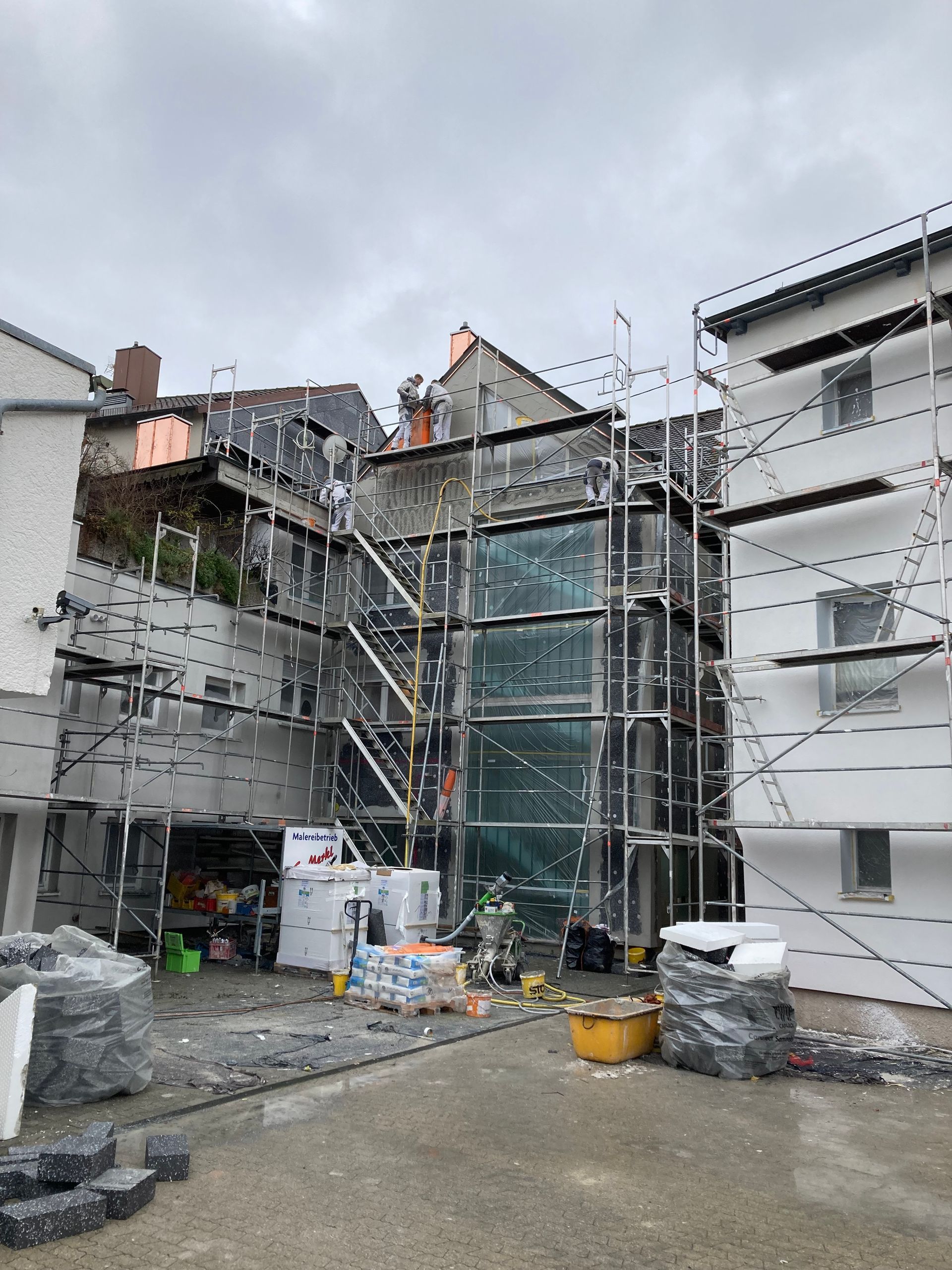 Gebäude wird renoviert, an der Seite sind Gerüst und Isolierung sichtbar.