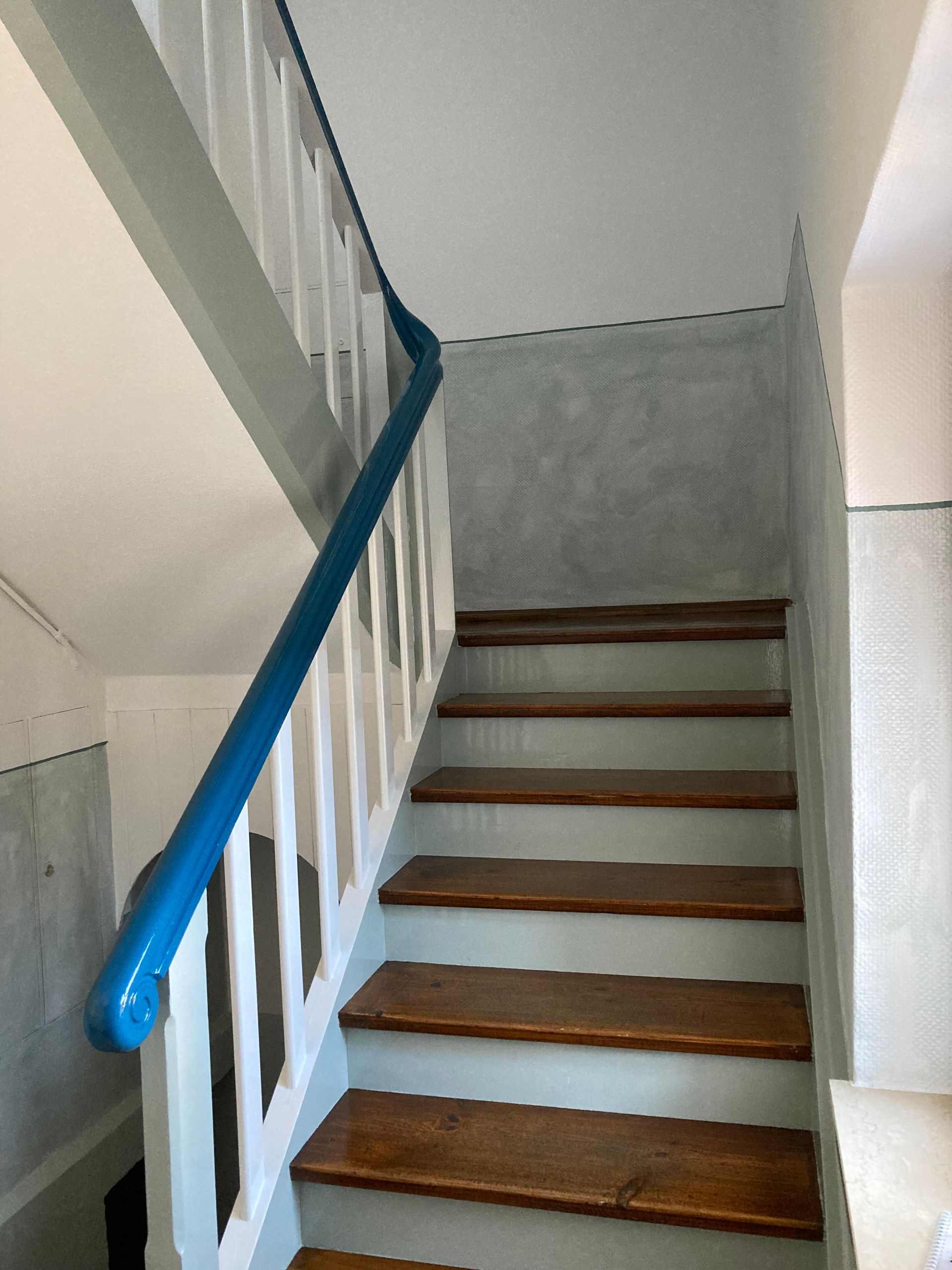 Graue Farbe mit einer Rolle auf eine weiße Wand auftragen.