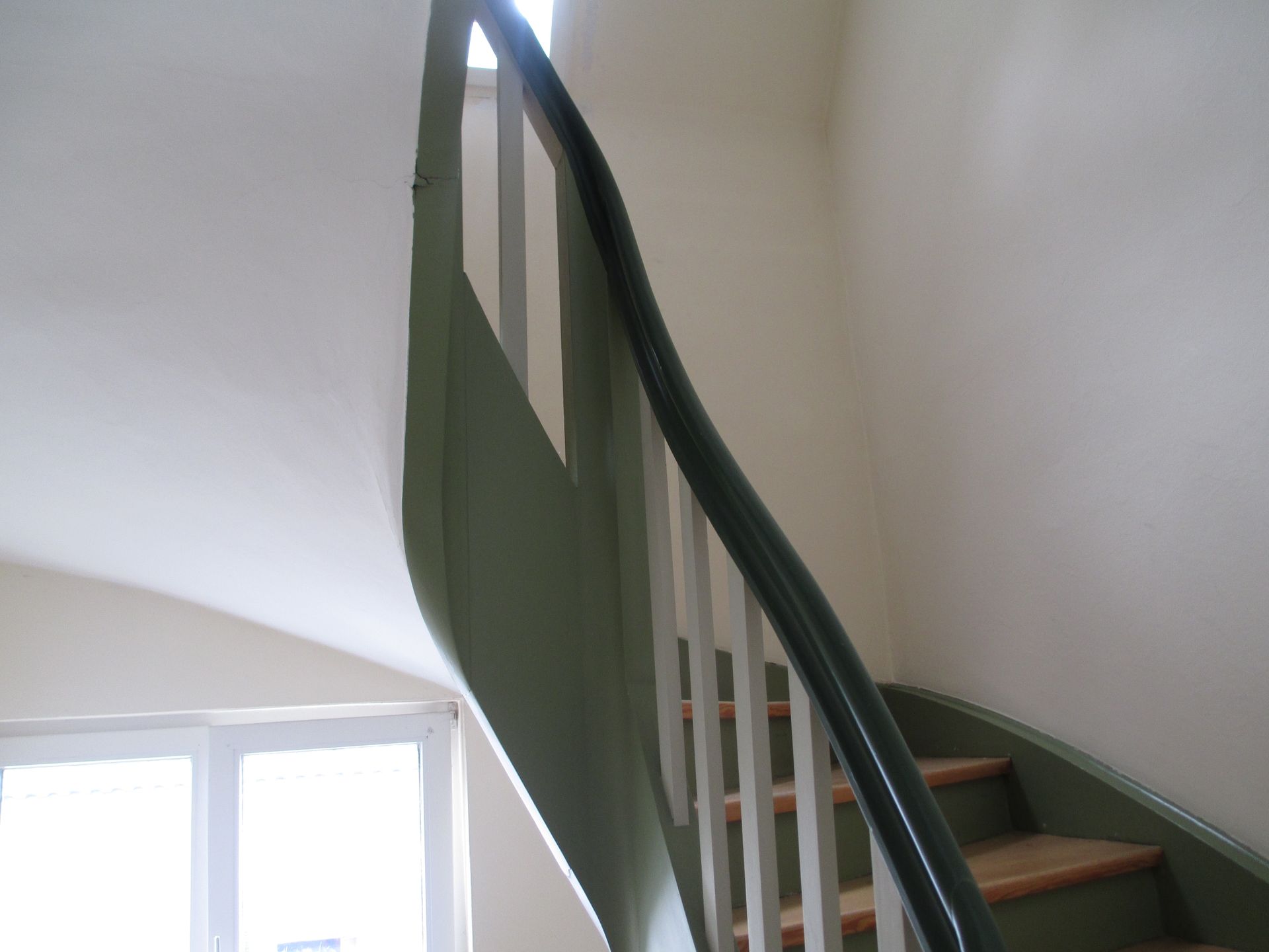 Person, die mit einer Spezialrolle Strukturfarbe auf eine Außenwand aufträgt.