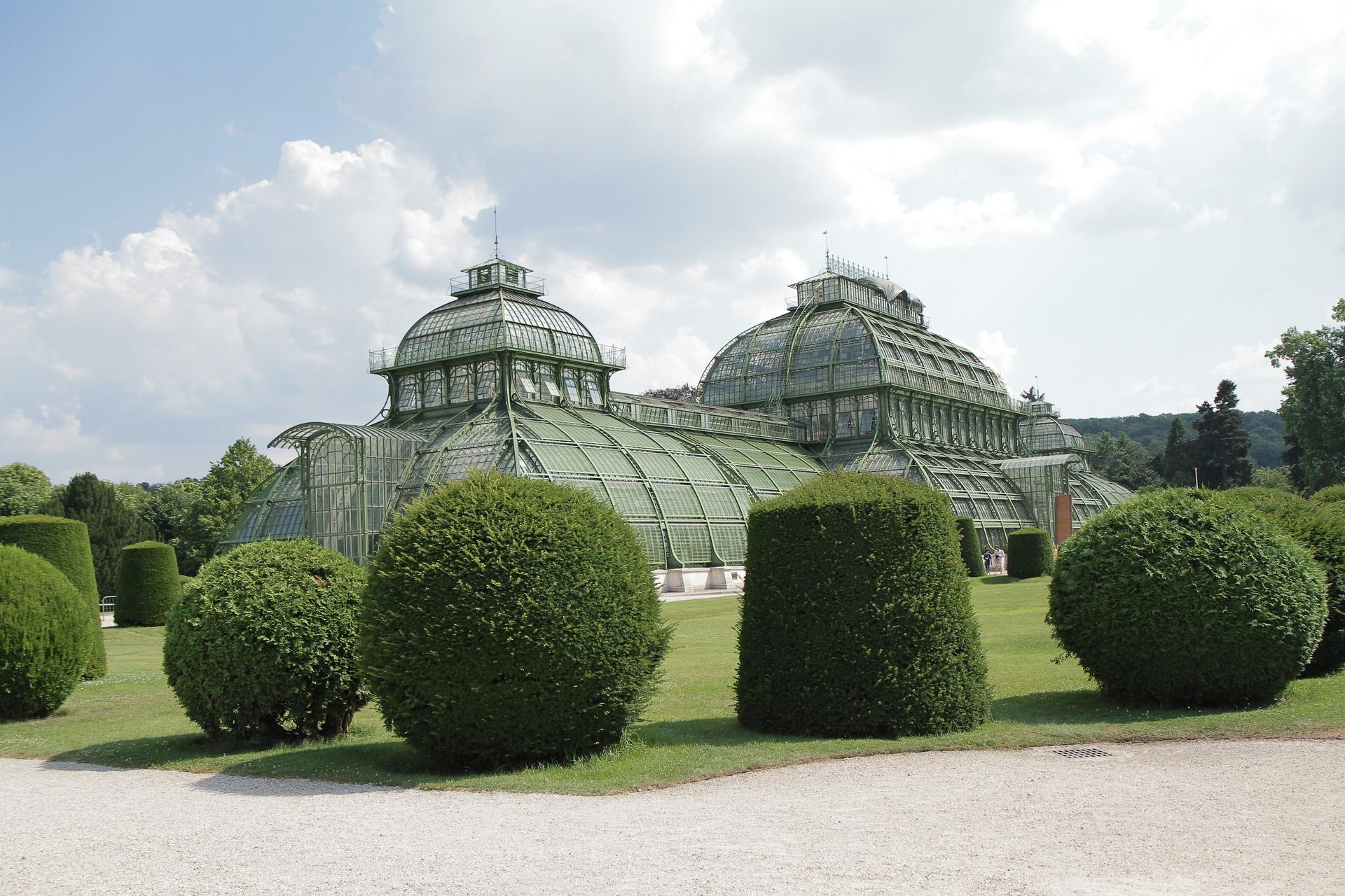 Jardin botanique avec des serres en verre et des buissons taillés.