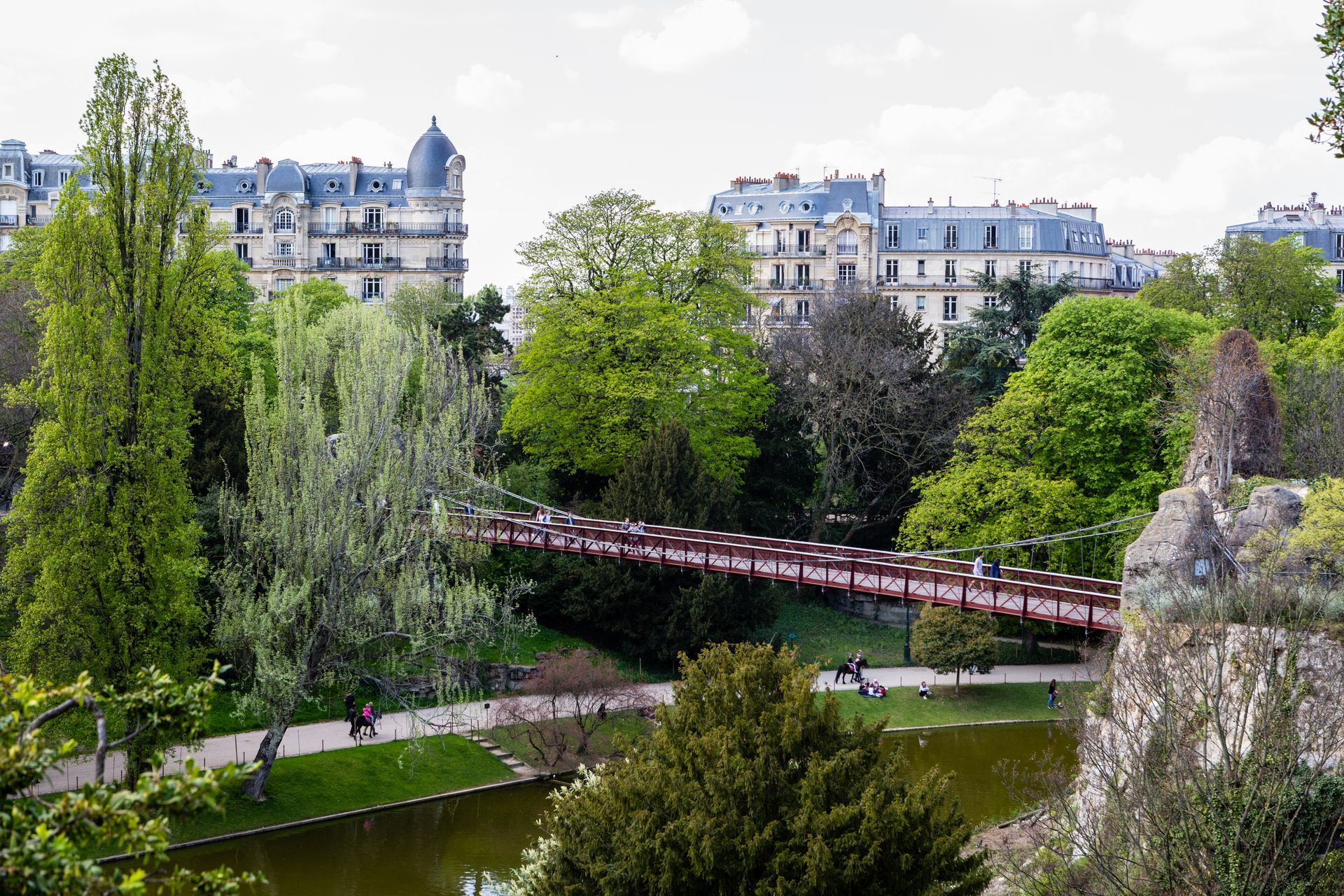 Vue d'un parc urbain avec un pont et des arbres verdoyants.