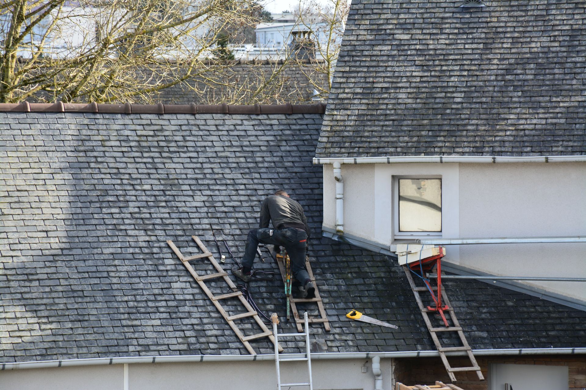 Une personne de dos sur une toiture en ardoise.