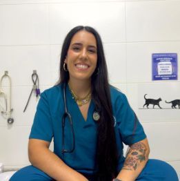 Una mujer sostiene en sus brazos un pequeño perro blanco y negro.