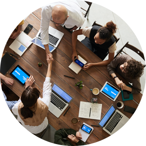 Un grupo de personas está sentado alrededor de una mesa con computadoras portátiles y tabletas.
