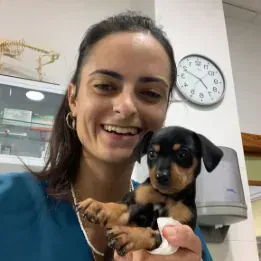 Una mujer sostiene un cachorro en sus brazos y sonríe.