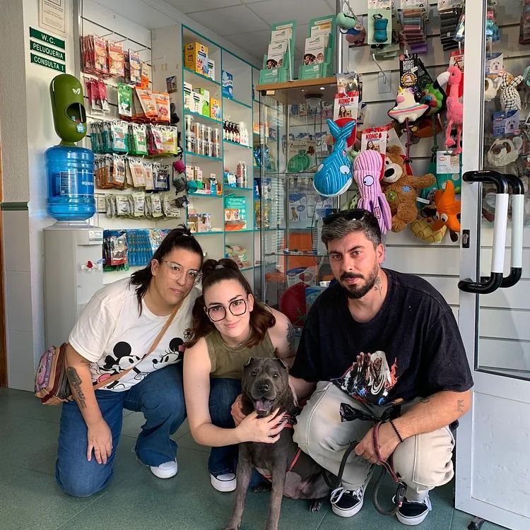 Un grupo de personas posa para una foto con un perro en una tienda.