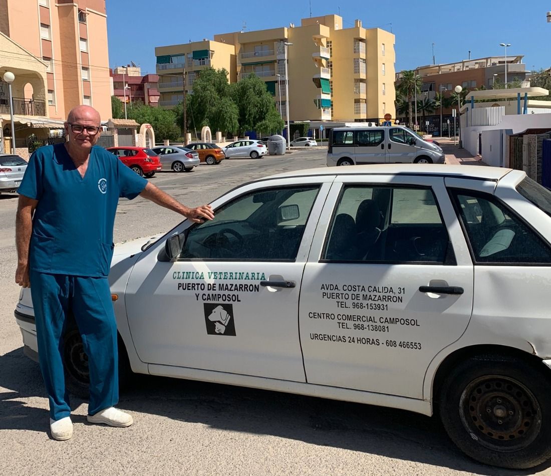 Un hombre con uniforme médico está de pie junto a un coche blanco que dice China.