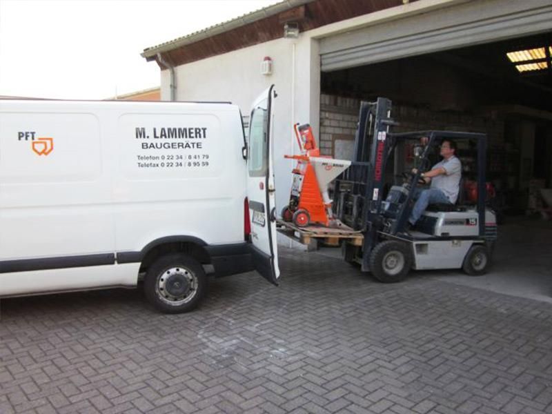 Ein Mann fährt mit einem Gabelstapler neben einem weißen Lieferwagen her.