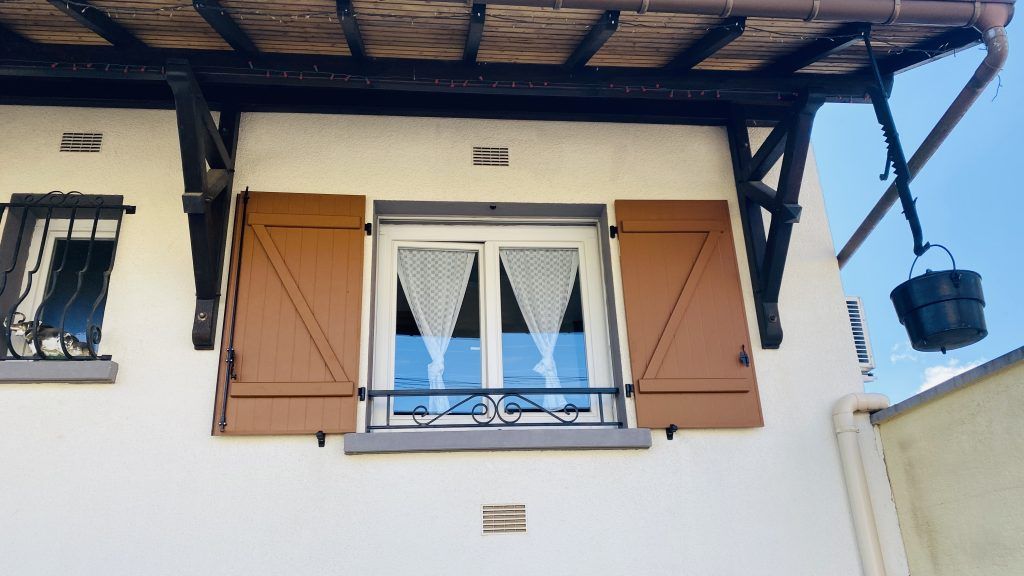 Photo de volets battants neufs en bois autour d'une fenêtre