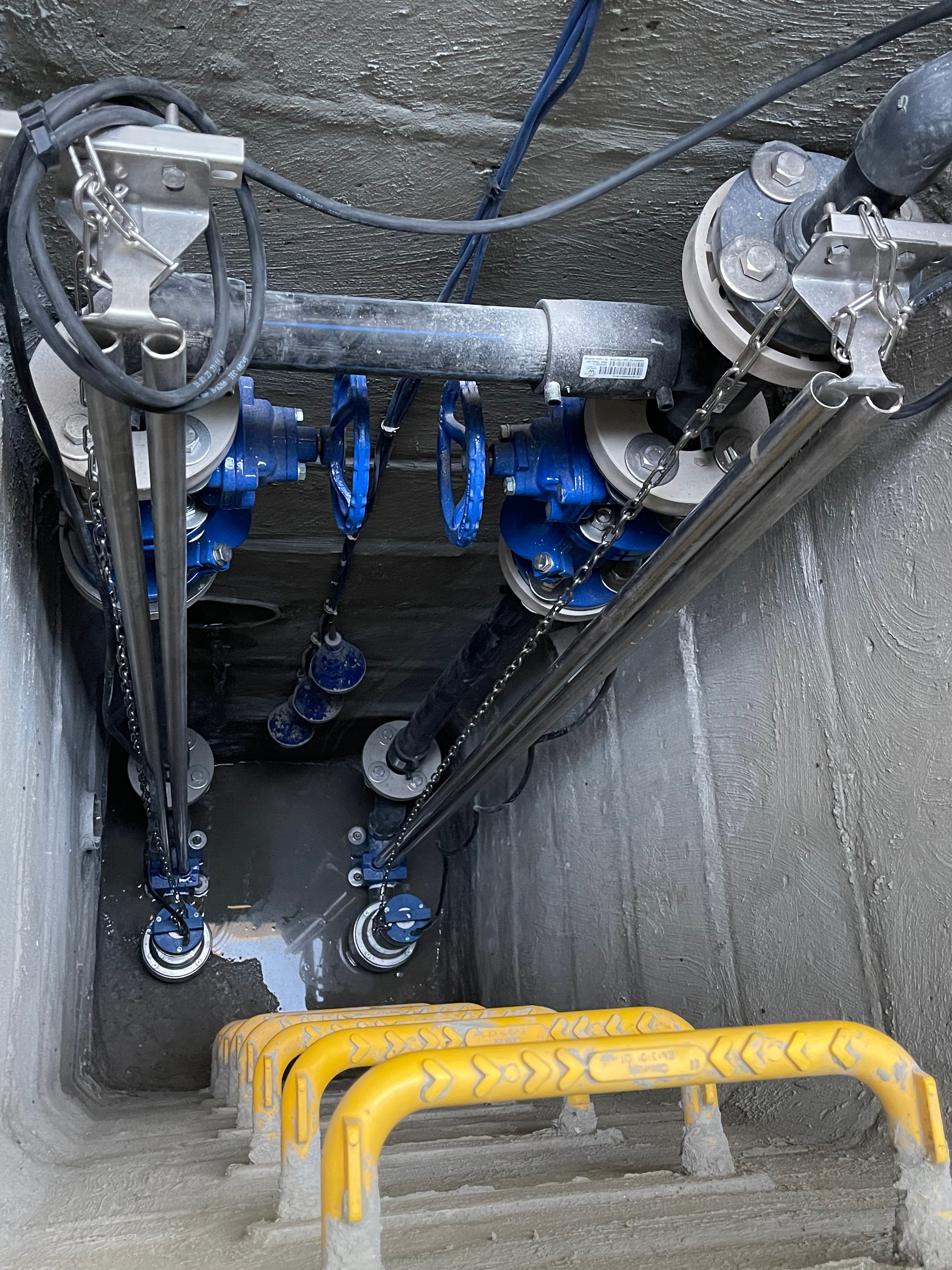 Un escalier menant à un drain avec un tas de tuyaux et de vannes.