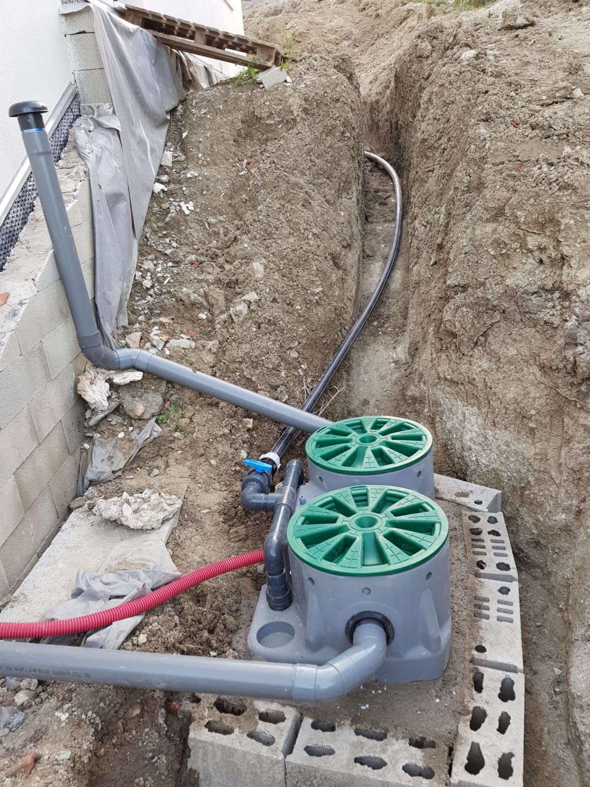 Un système de drainage est en train d'être installé dans un trou dans le sol.