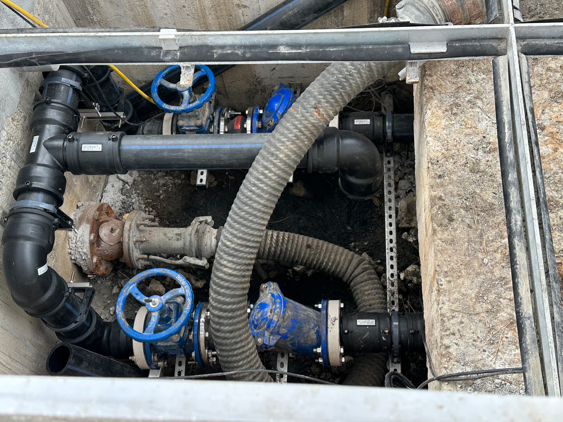 Un tas de tuyaux et de vannes se trouvent dans un trou dans le sol.