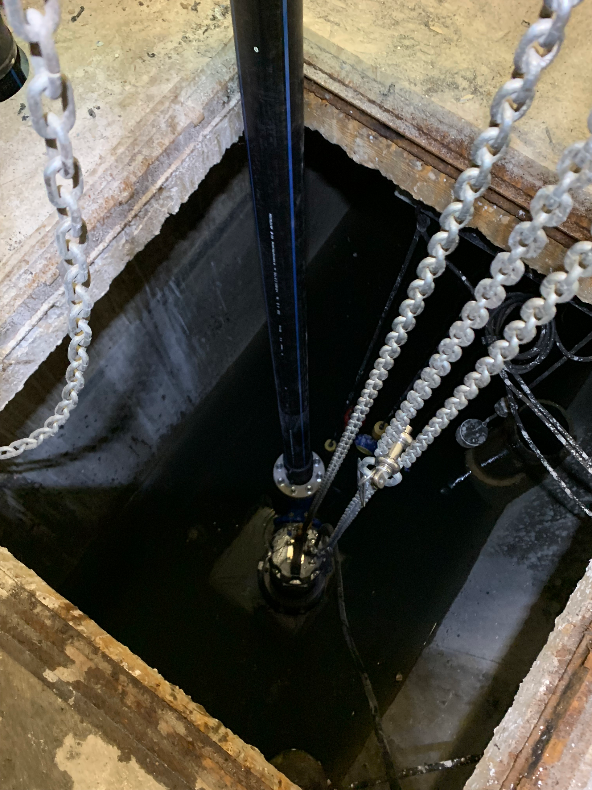 Une chaîne est suspendue à un tuyau dans un trou