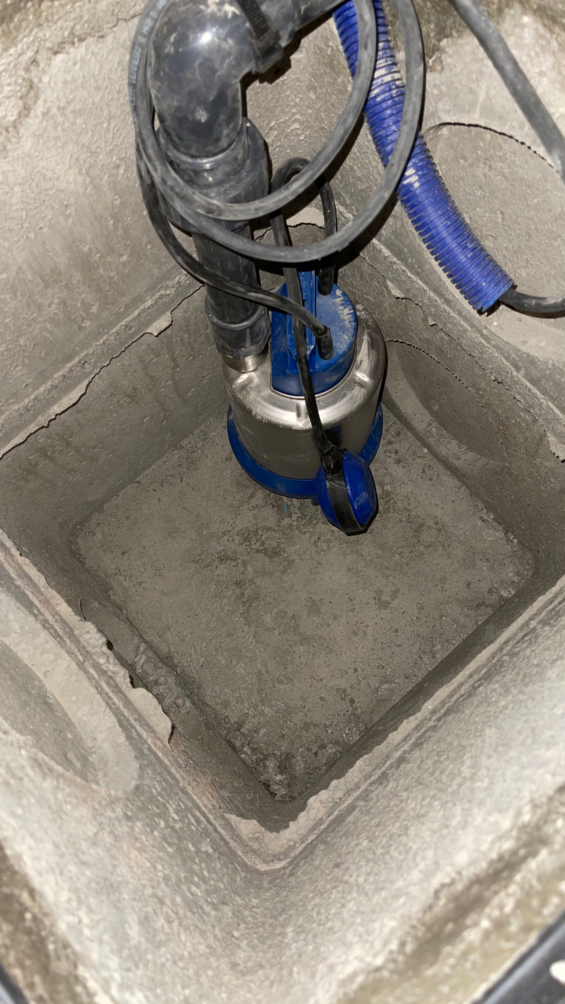 Une pompe bleue est assise dans un trou dans le sol.