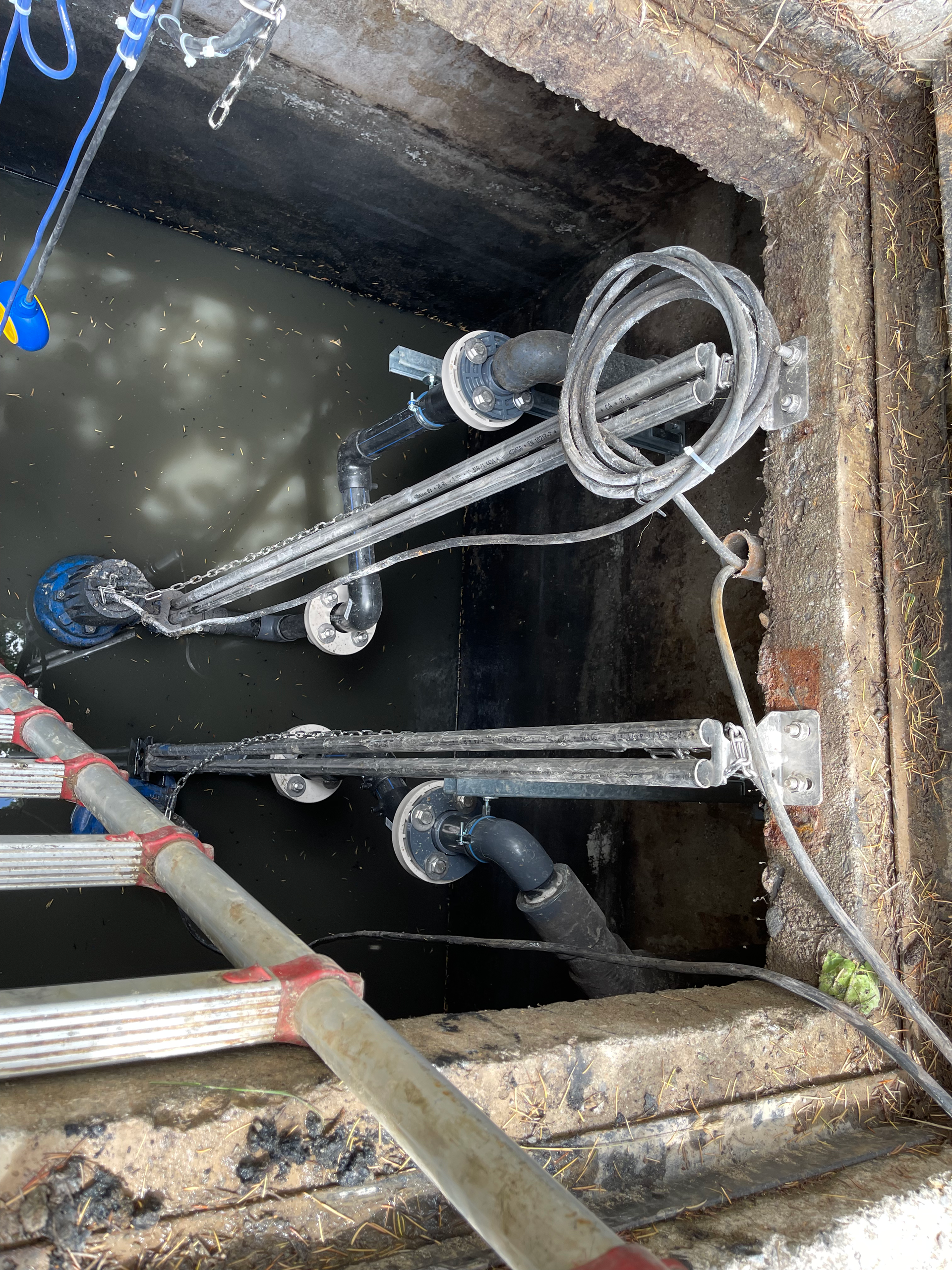 Un couvercle de trou d'homme avec des tuyaux et des fils qui en sortent.