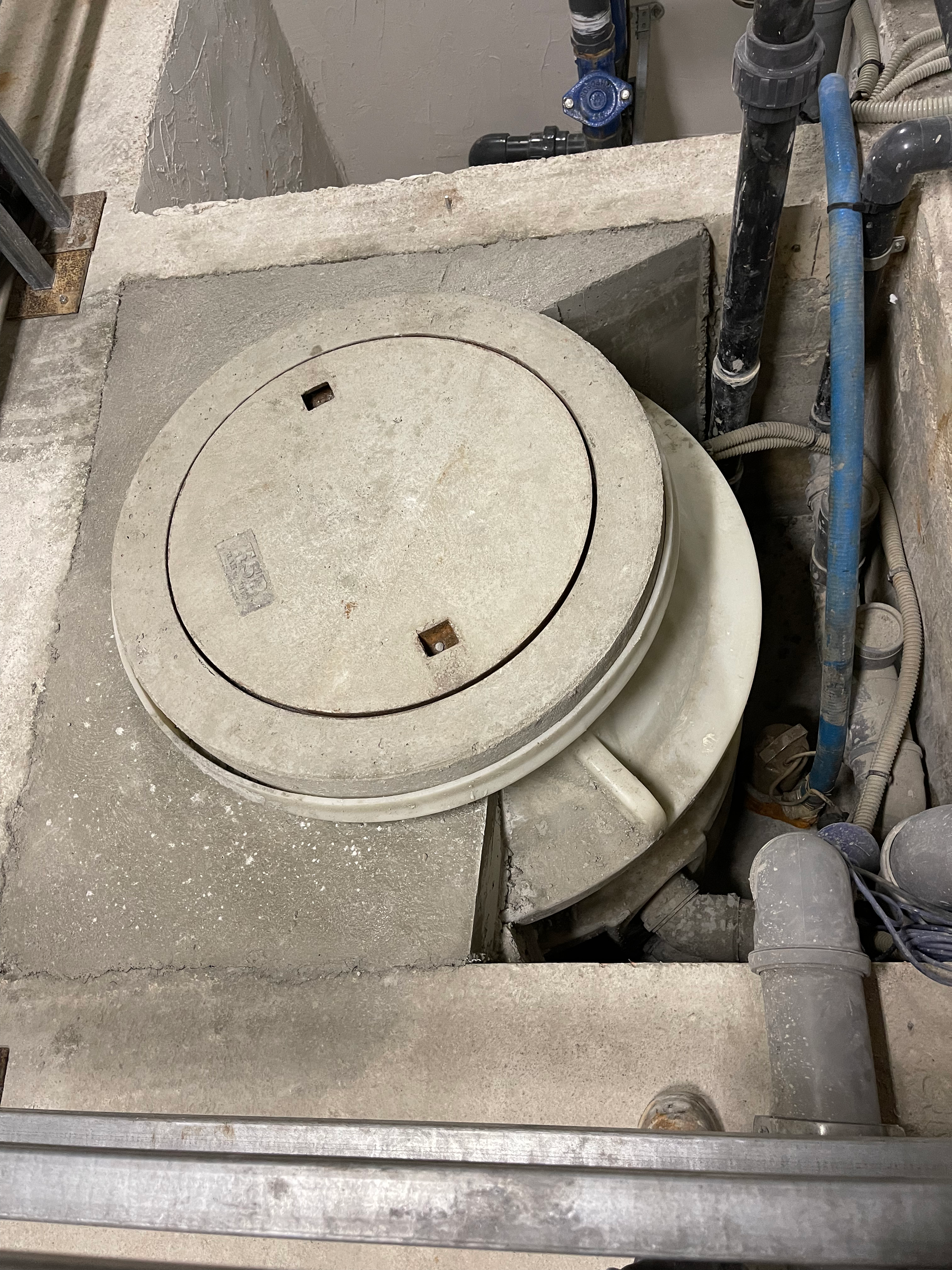 Un couvercle de trou d'homme est posé sur un bloc de béton.