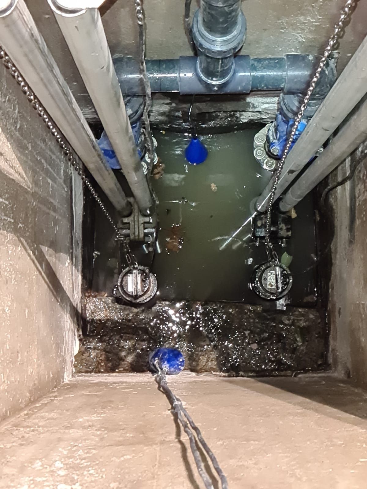 Un couvercle de trou d'homme rempli d'eau et de tuyaux.