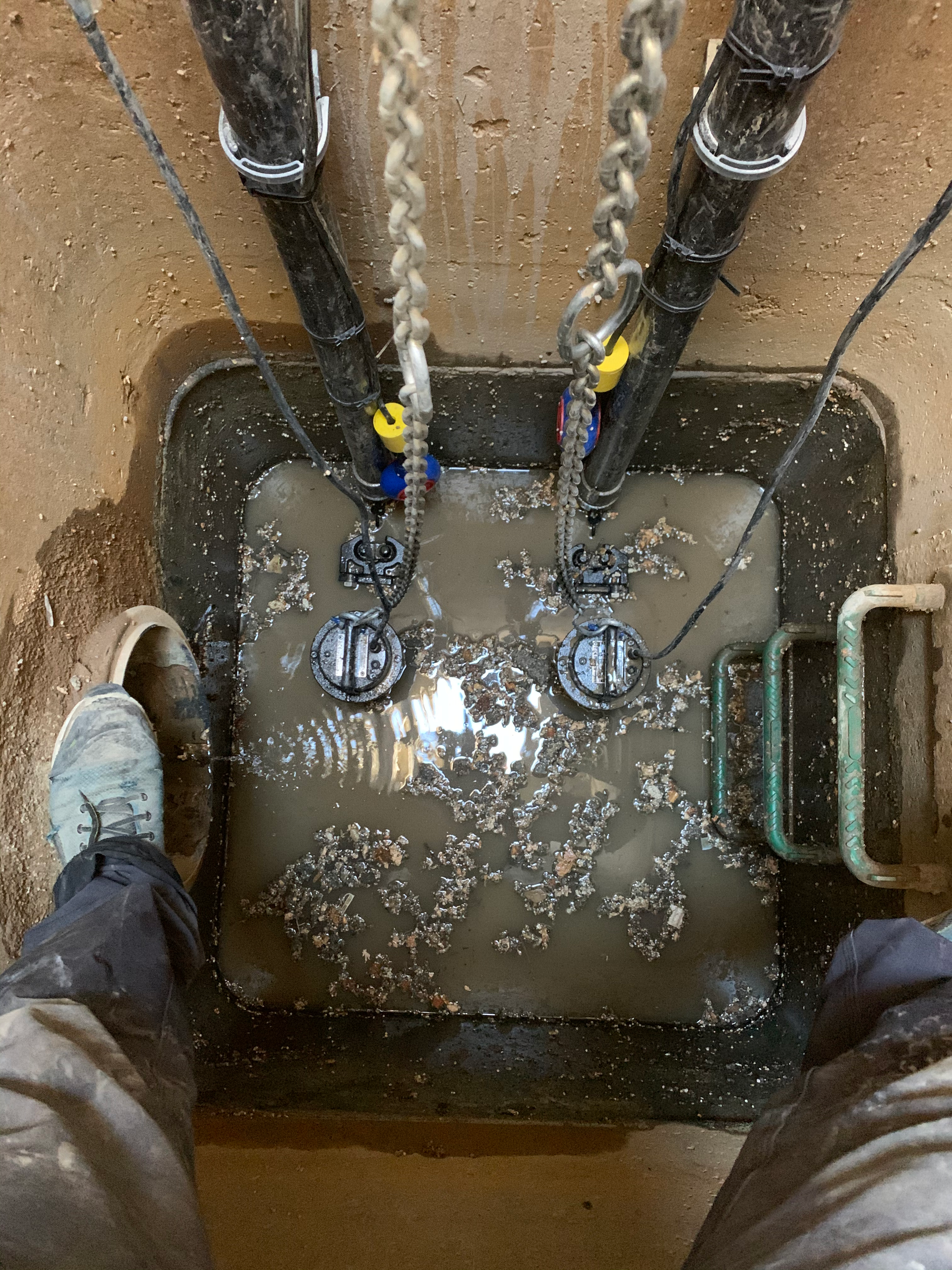 Une personne se tient debout dans un trou boueux avec une chaîne qui y est suspendue.