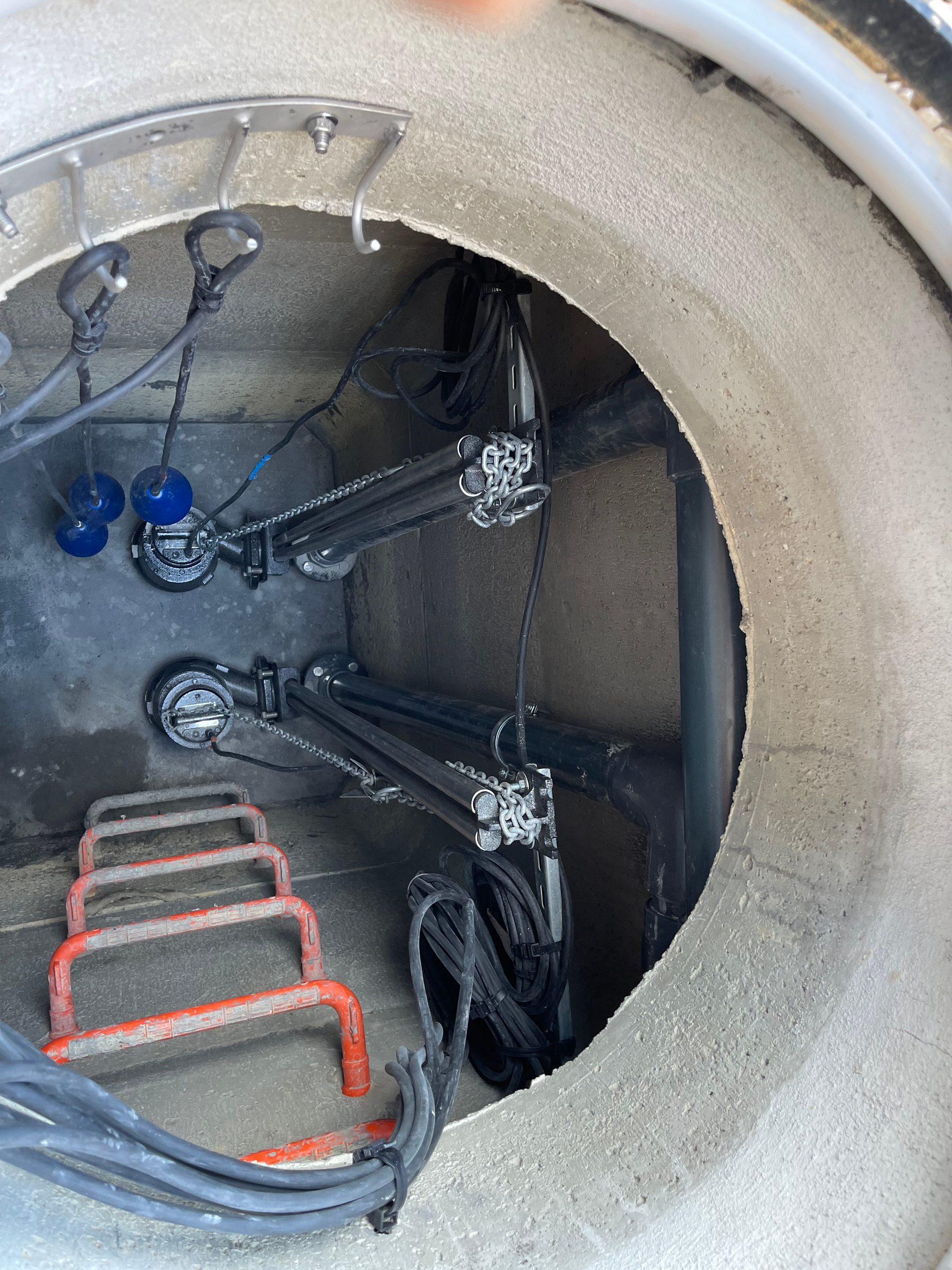 Un couvercle de trou d'homme avec une échelle et un tas de fils qui en sortent.