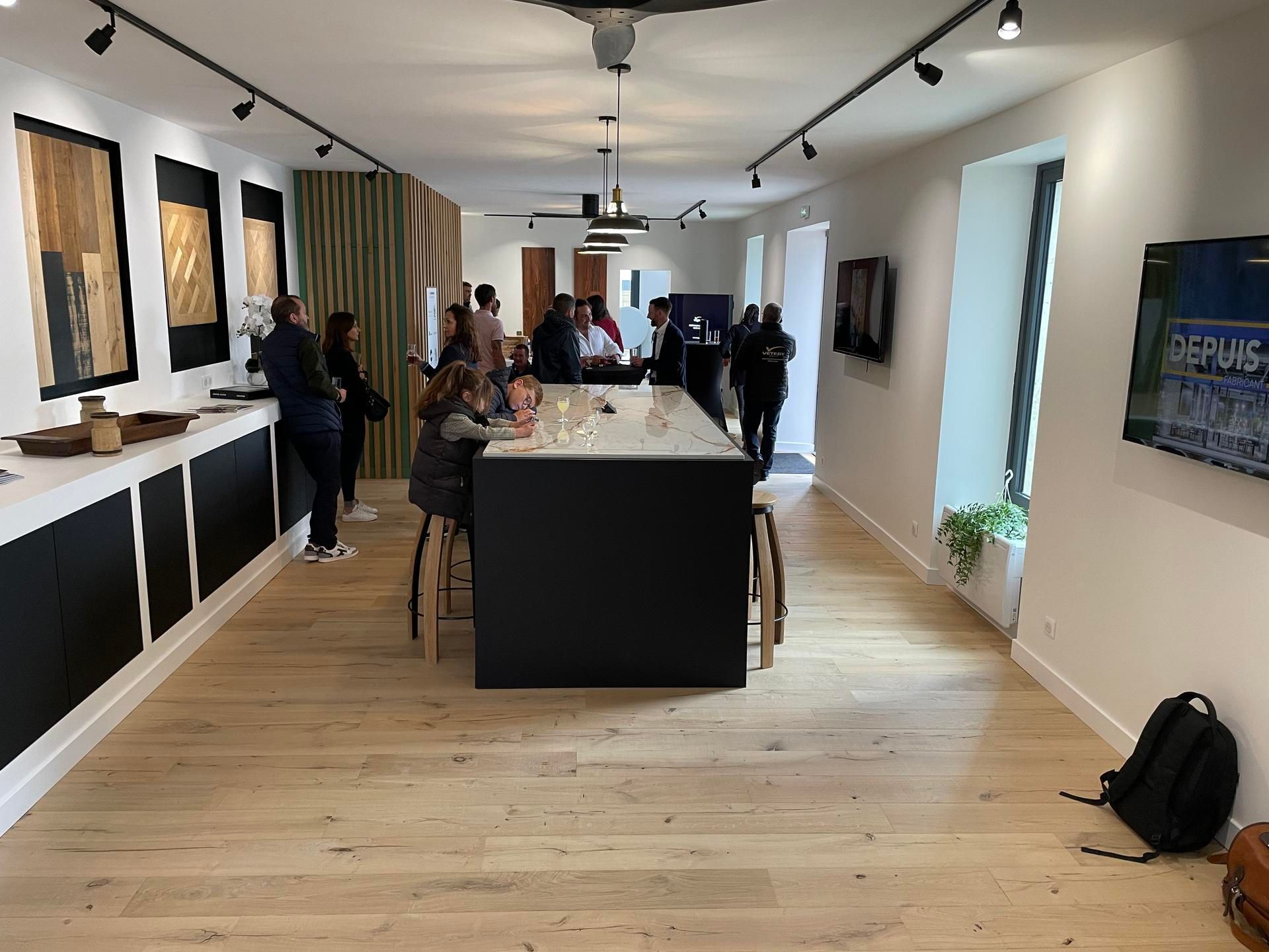 Des personnes dans une galerie d'art avec un bar et un parquet.