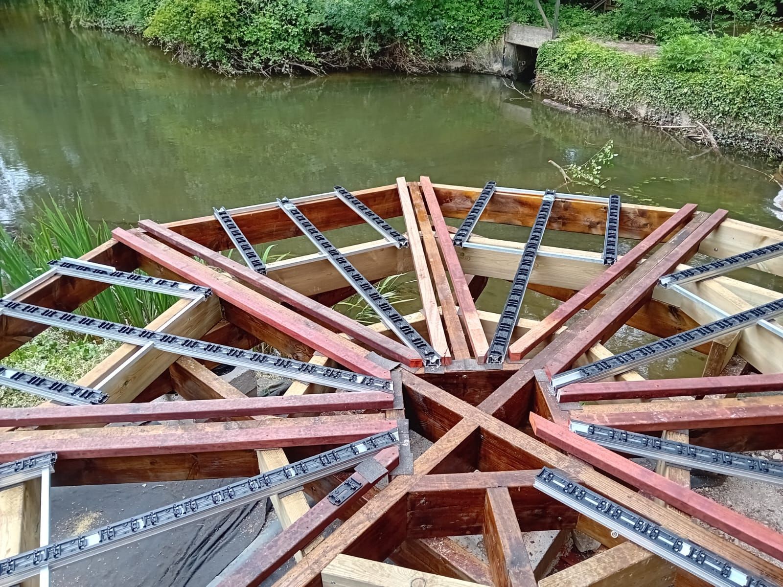 Roue à eau en bois en construction près d'un étang.
