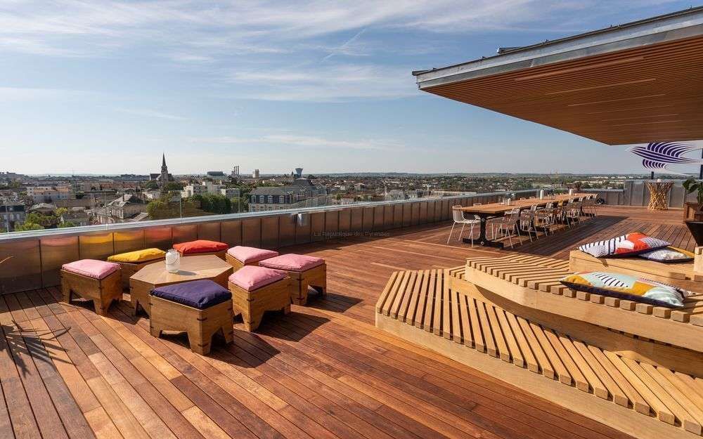 Terrasse sur le toit avec plancher en bois, sièges et vue sur la ville.