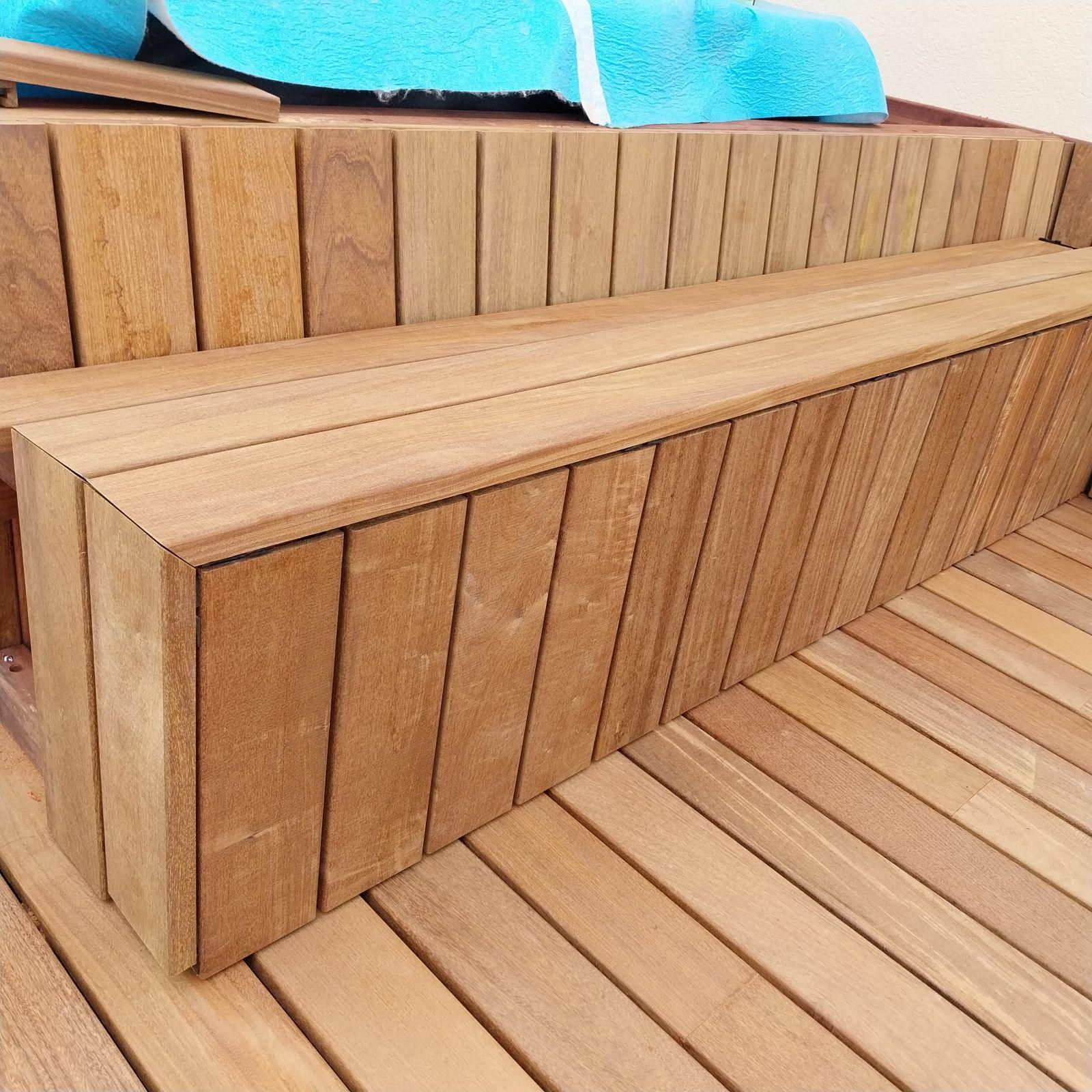 Banc et marches en bois près d'une piscine ou d'un spa, construits avec des planches verticales.