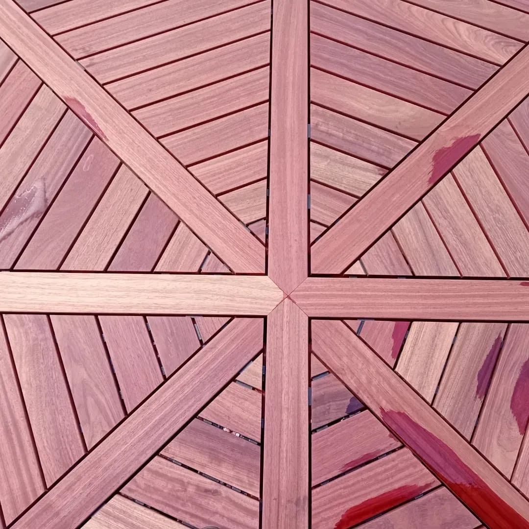 Plancher en bois composé de lames rouge violet disposées selon un motif géométrique en forme de croix.