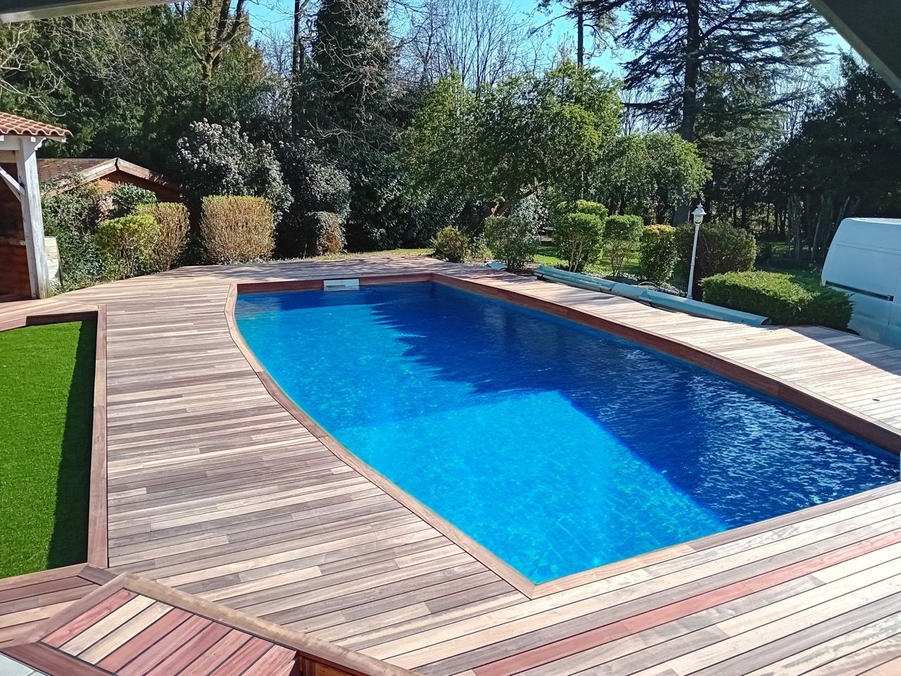 Piscine aux eaux bleues entourée d'une terrasse en bois.