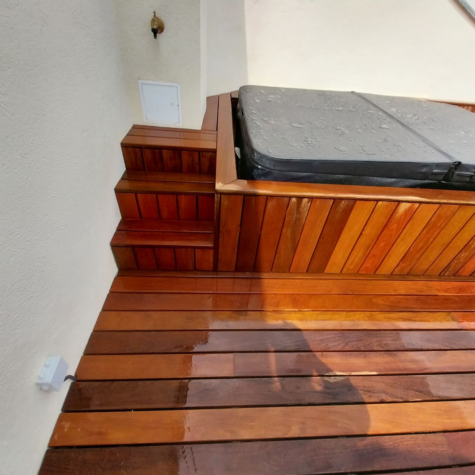 Terrasse en bois avec jacuzzi intégré. Un escalier mène au jacuzzi. Tons bruns chauds dans toute la maison.