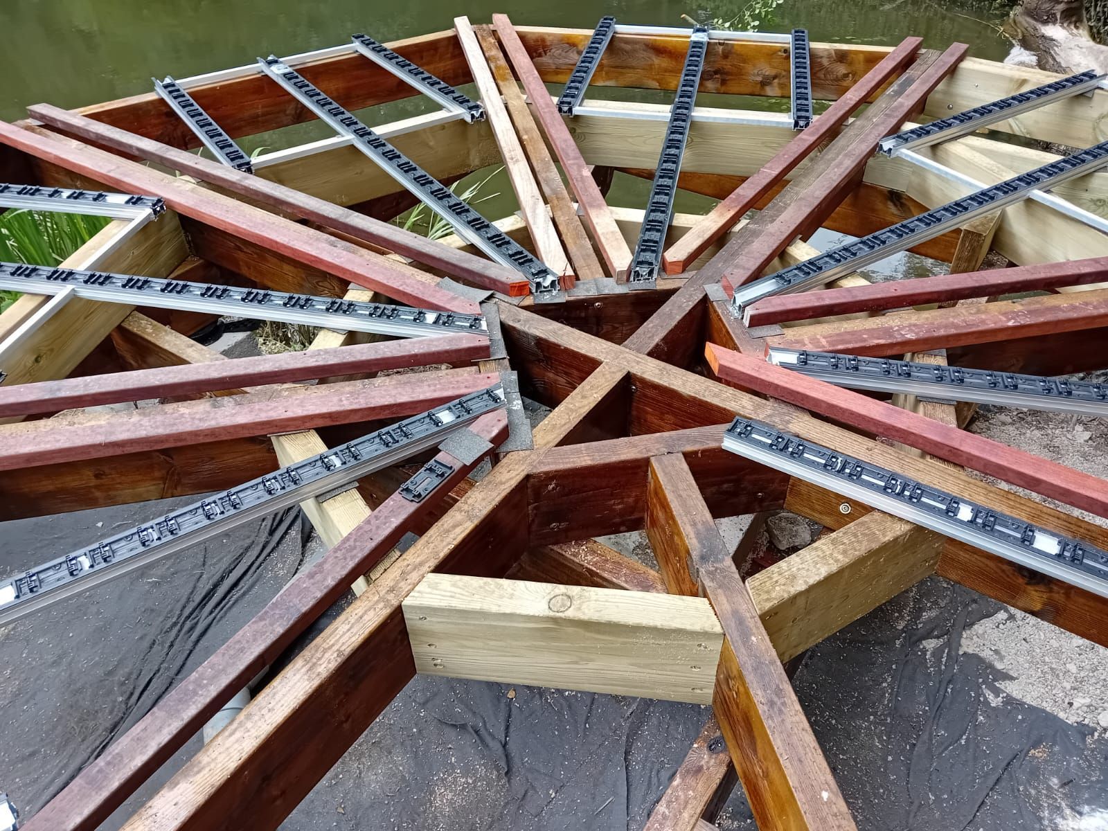 Construction à ossature bois avec poutres rayonnantes, supports métalliques et jonction centrale.