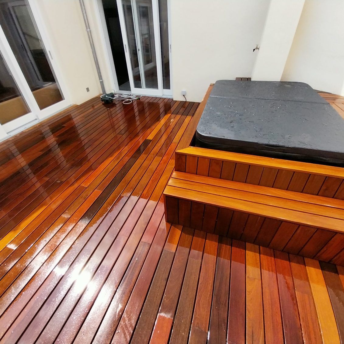 Terrasse en bois avec marches menant à un jacuzzi.