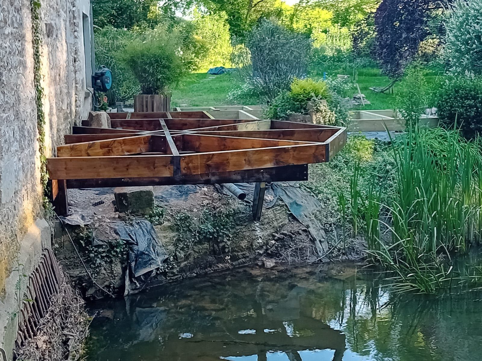 Terrasse en bois en construction au bord d'un plan d'eau.