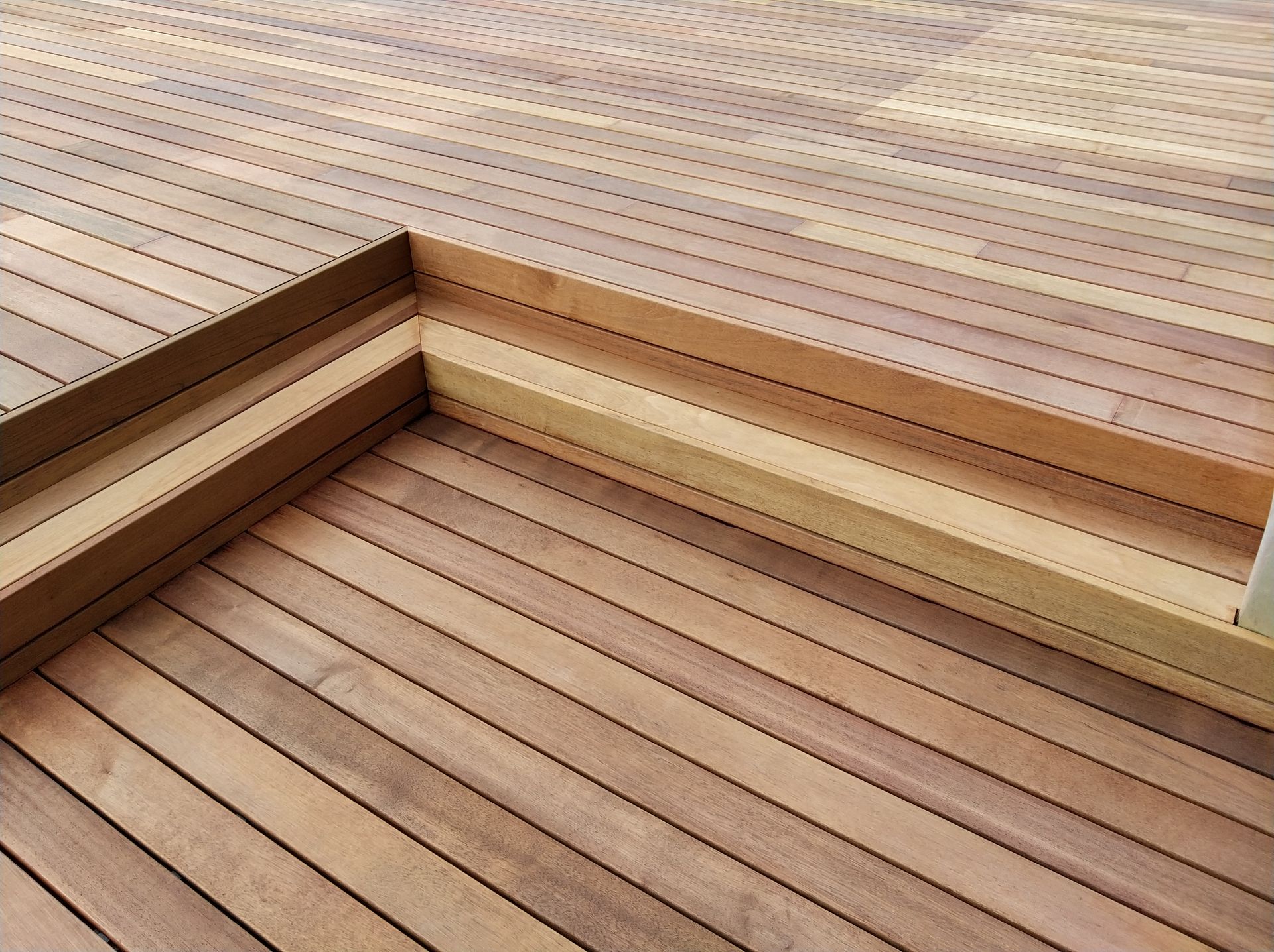 Terrasse en bois avec marches intégrées, planches horizontales, différents niveaux, tons de bois naturel.