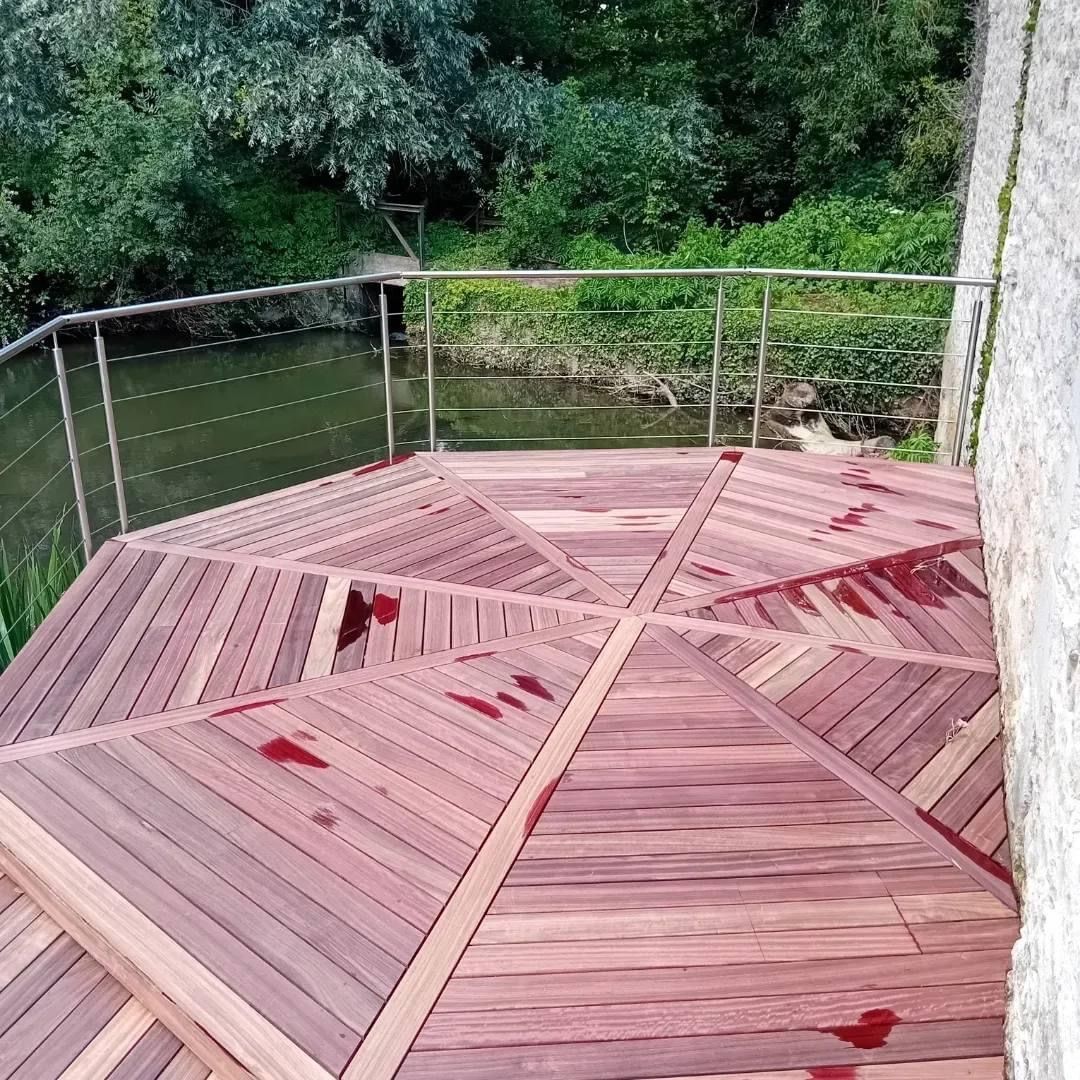 Terrasse en bois avec rambarde donnant sur une rivière.