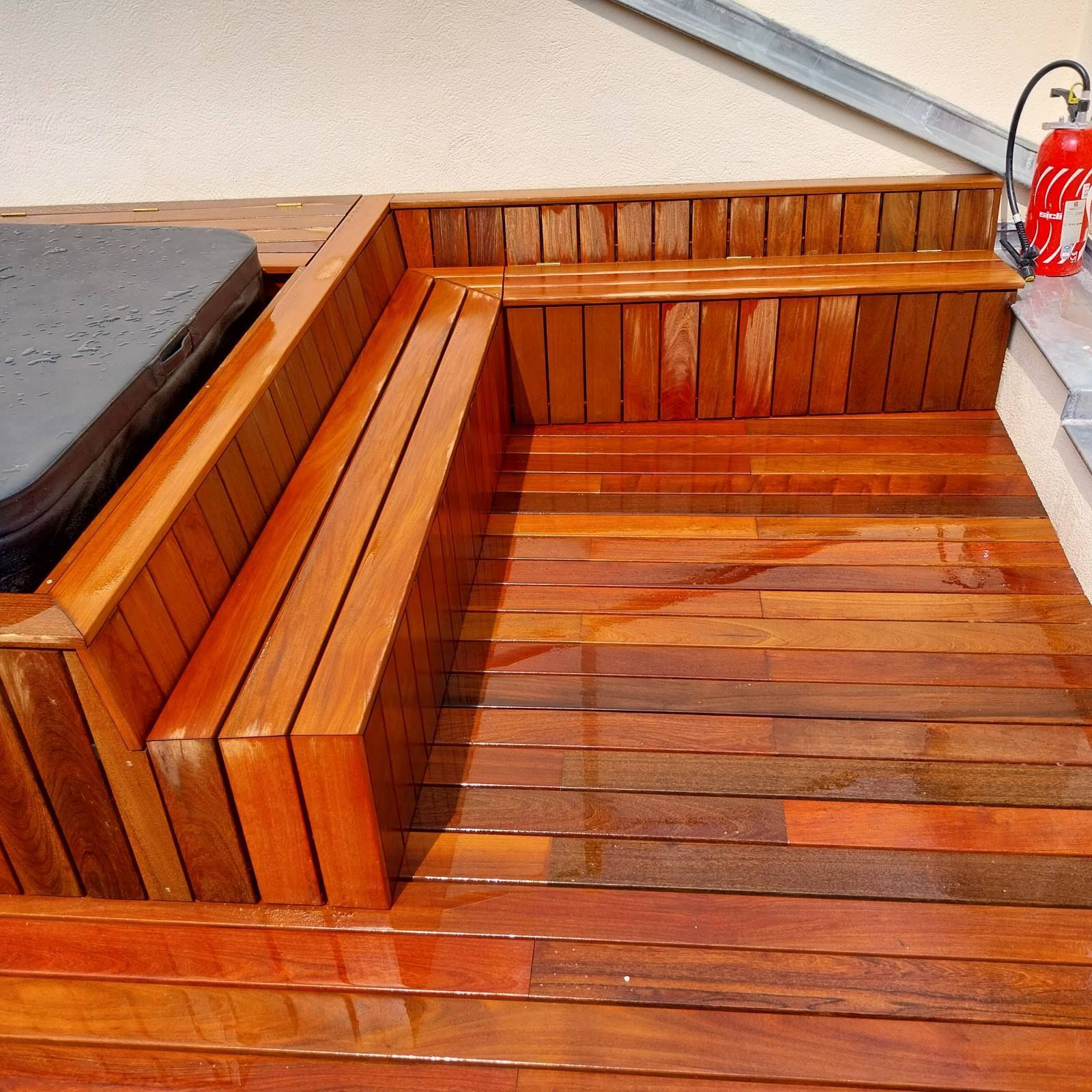 Terrasse en bois avec banquettes intégrées autour d'un jacuzzi.
