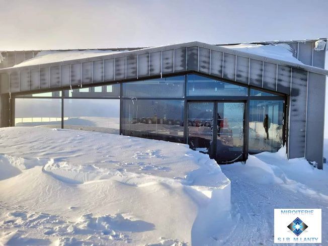 Bâtiment enneigé en haute montagne avec une façade totalement vitrée