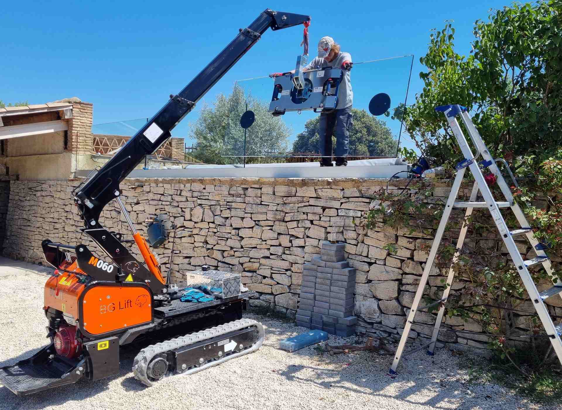 Technicien de Sib M Lanty posant une vitre sur un haut mur en pierre
