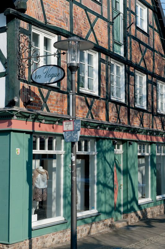 Ein Fachwerkhaus mit grüner Fassade und einer Straßenlaterne davor.