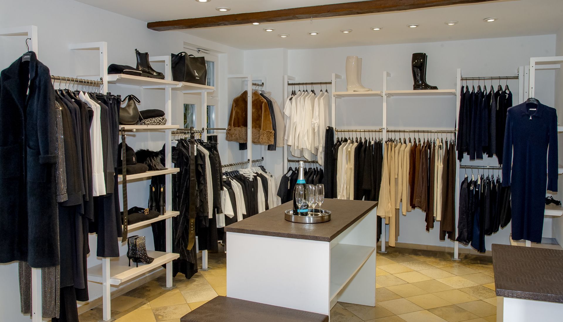 Eine Frau hält einen rosa Pullover vor einem Ständer mit Pullovern.