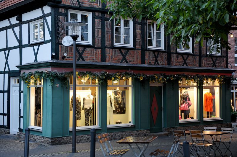 Ein grün-weißes Gebäude mit Tischen und Stühlen davor.